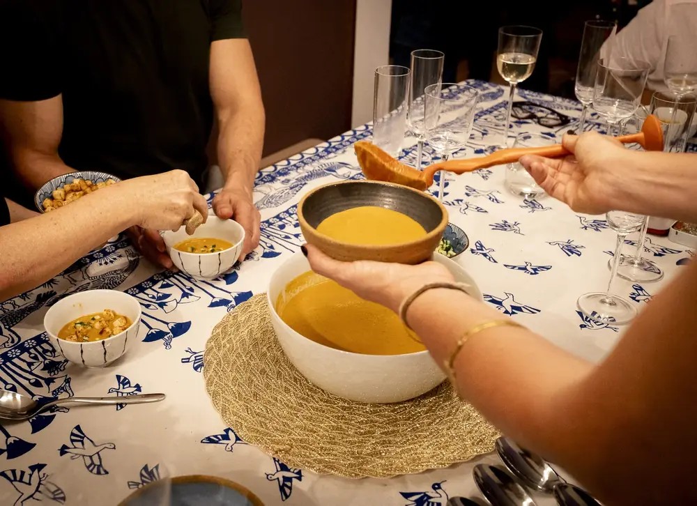 Mãos servindo creme em tigelas na mesa posta