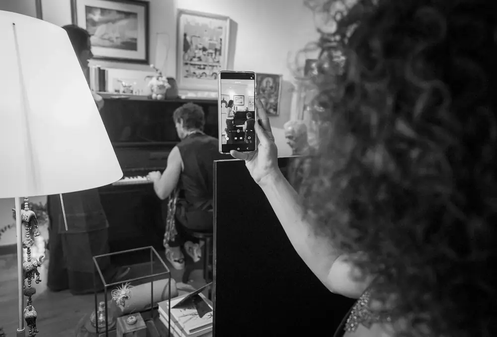 Convidado ao piano e convidada filmando, em preto e branco